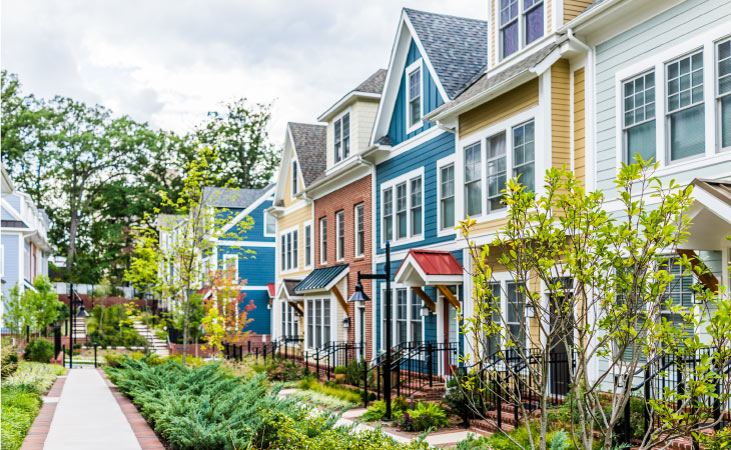  A row of colorful townhouses with vibrant lawns and greenery in their small front yards.