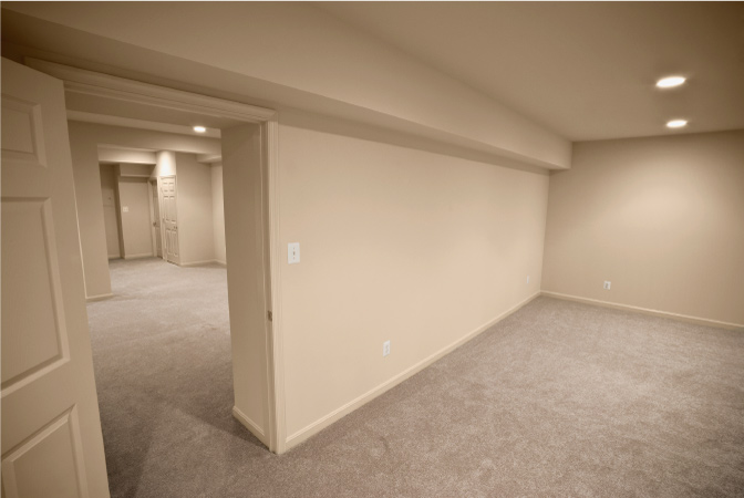 A finished basement that’s been divided into two separate rooms with a new wall and doorway.