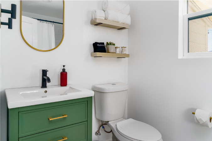 A small 4x5 bathroom with a white toilet and sage green vanit