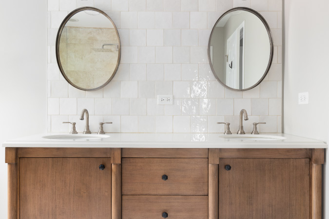 A bathroom vanity with two sinks and wooden cabinets