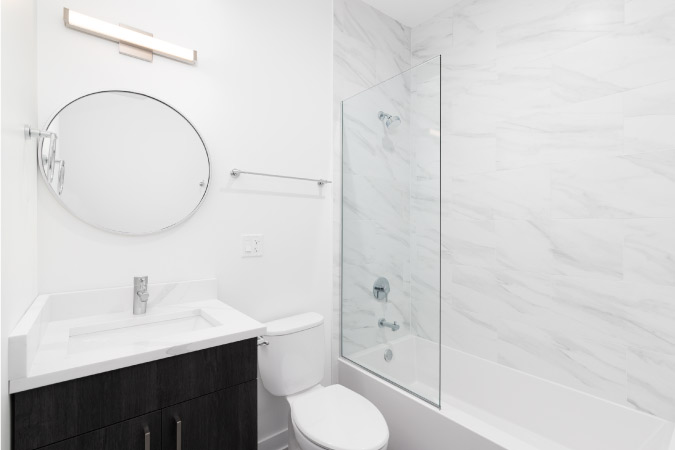 A small bathroom featuring a bathtub/shower combo, toilet, and single vanity