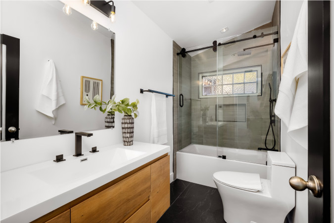 A moderately sized bathroom with a toilet, shower/tub combo, and long vanity