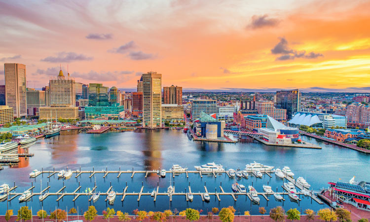 Aerial view of Baltimore, Maryland, including Inner Harbor and the surrounding city buildings during sunset.