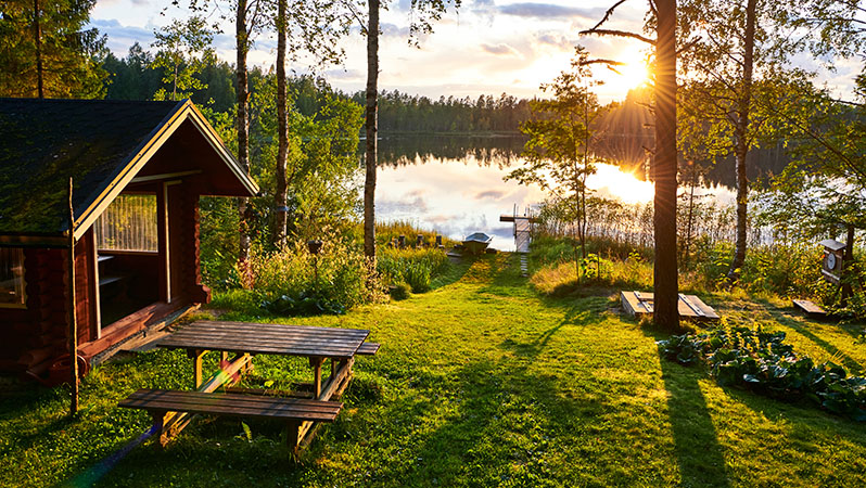 A picturesque lakefront yard with a picnic bench at sunset