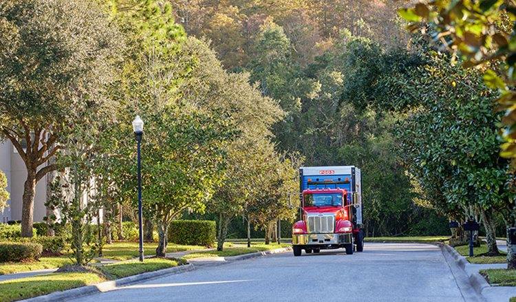 A PODS truck carrying a container down a residential street