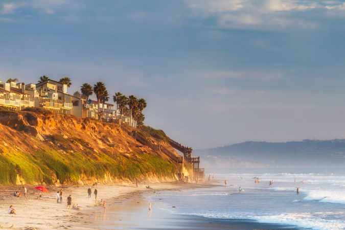 Dozens of locals enjoy a sunny day at South Carlsbad State Beach in Carlsbad, California. The steep cliffs above the beach are home to luxury waterfront residences.