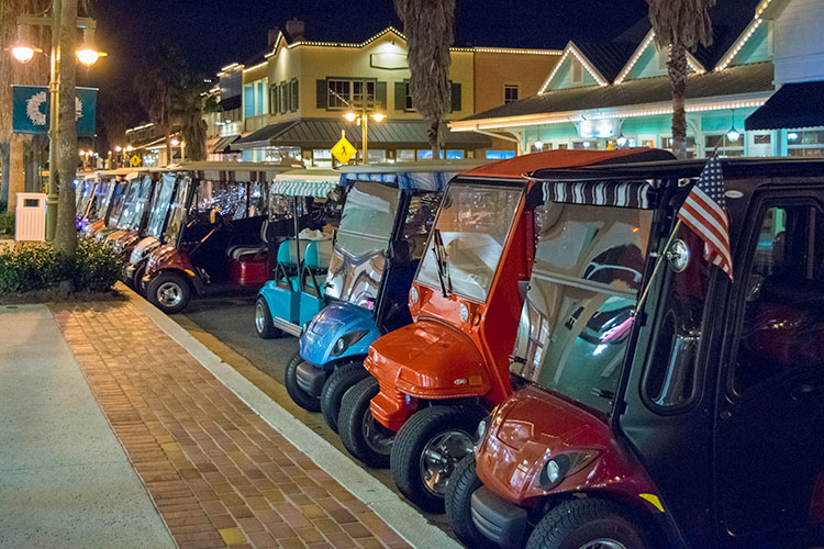 A group of golf carts parked along the curb in The Villages, Florida.