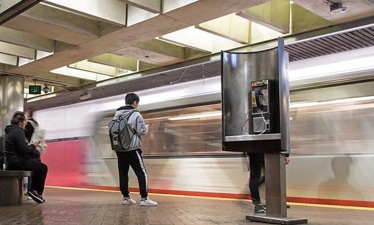 Passengers wait at a San Francisco trans authority station as a train zips by.