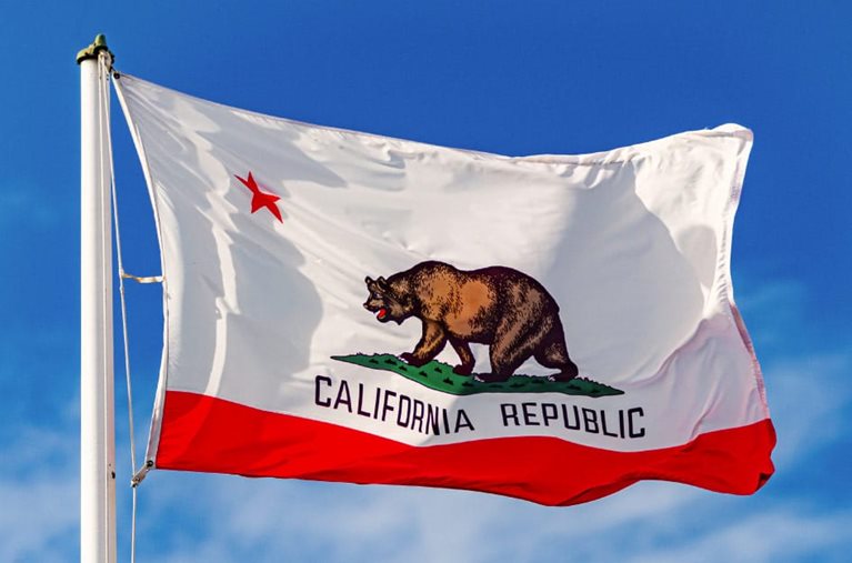 The California state flag flying in front a blue sky