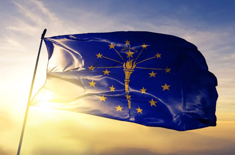 The Indiana state flag, blowing in the wind at the top of a flagpole.