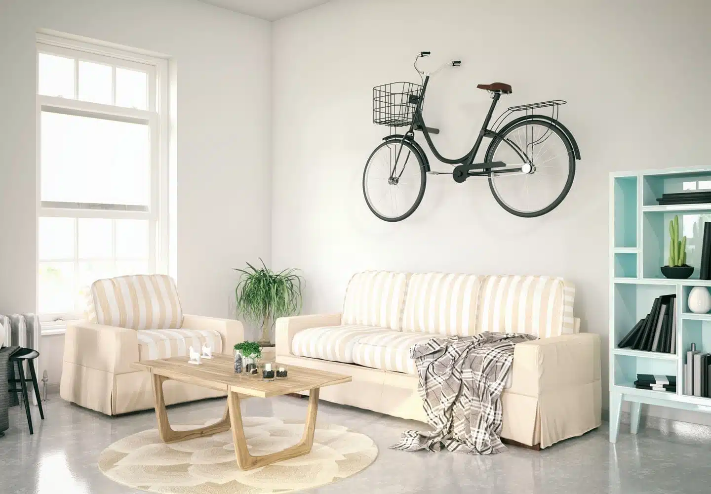 A small apartment living room with a sofa, loveseat, small coffee table, stocked bookshelf, and a bike hung on the wall to save space