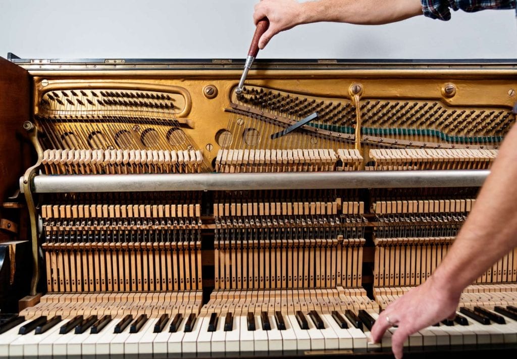a piano tuner working on an upright piano