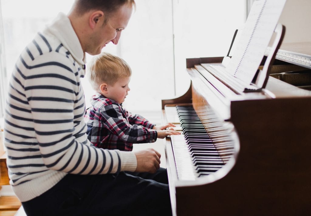 a father watching his son play piano