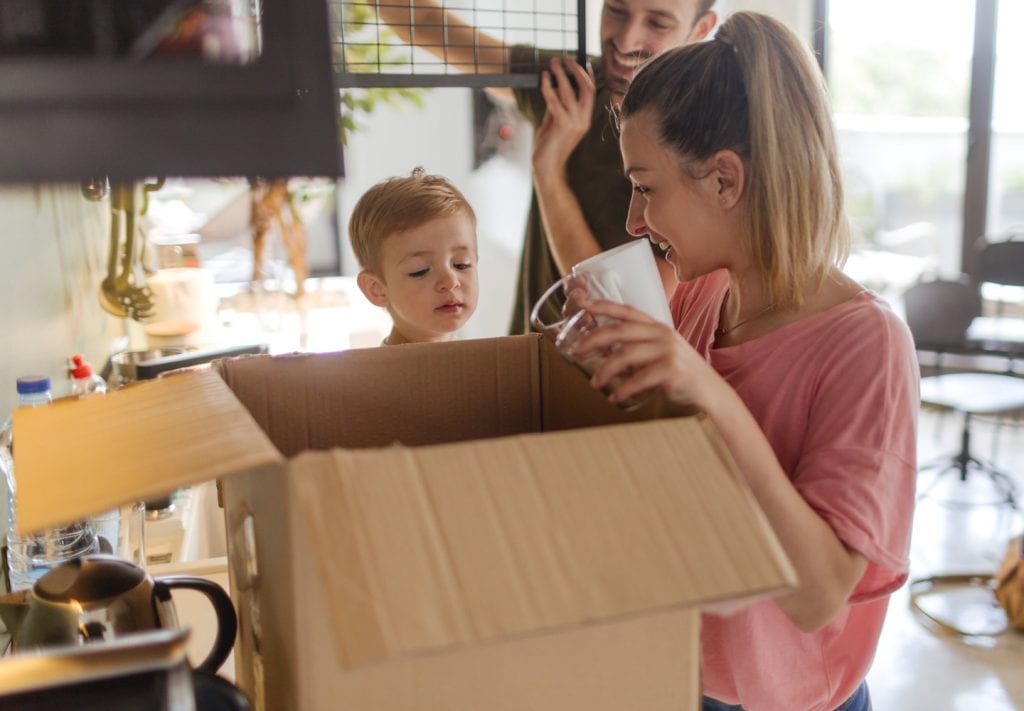 A young family packing dishes in a moving box