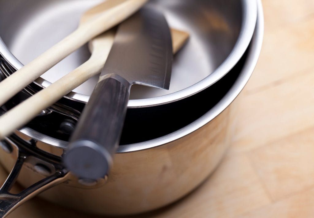 Kitchen tools in stacked metal cooking pots