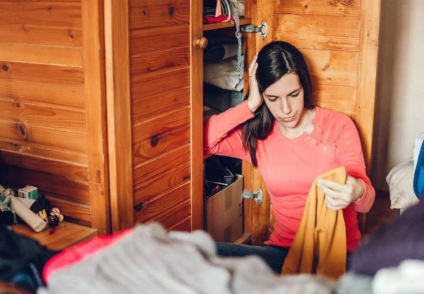 A recent college graduate looks stressed as she tries to downsize her closet.