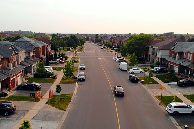 A car drives through an American suburb, scouting out the neighborhood and looking for a perfect home