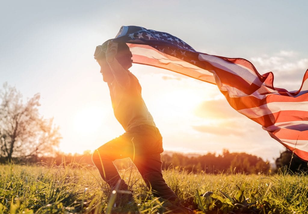 A boy runs, holding the American flag