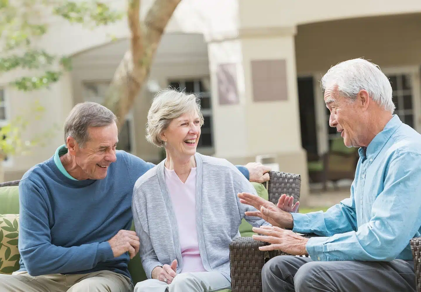 Three mature adults sit around at a rec center laughing.