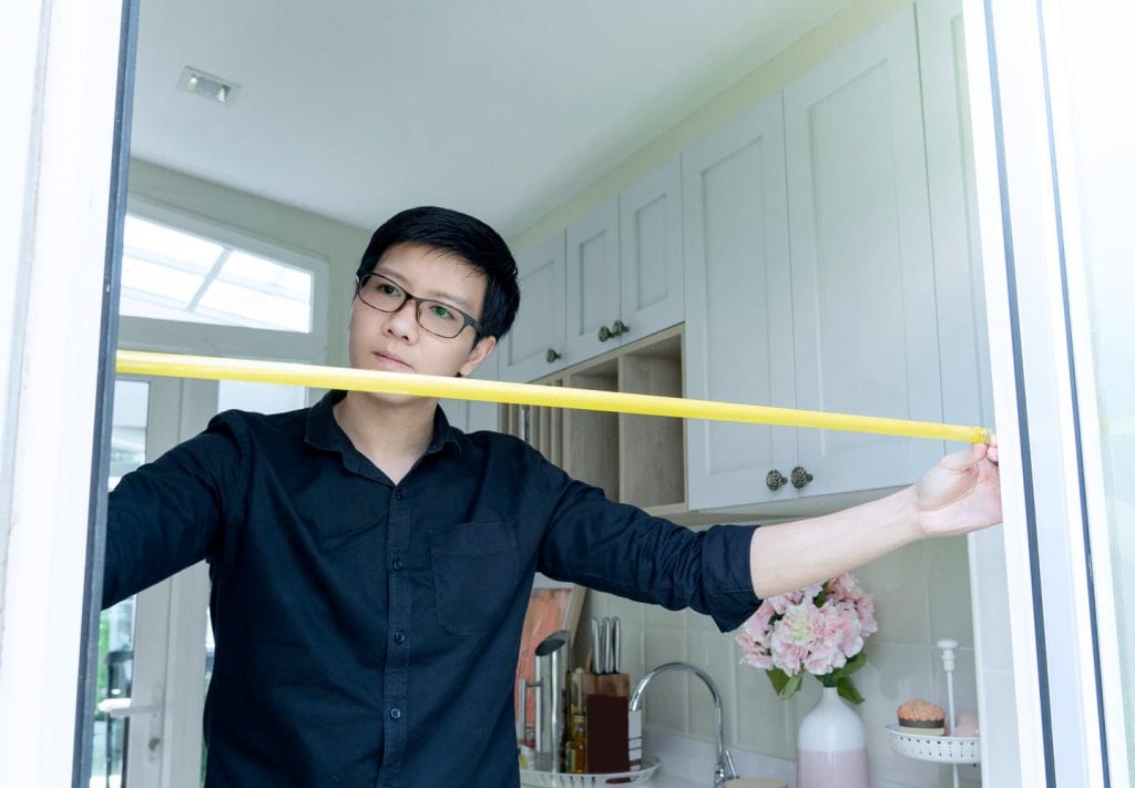 man measuring a door frame to prepare for moving a piano