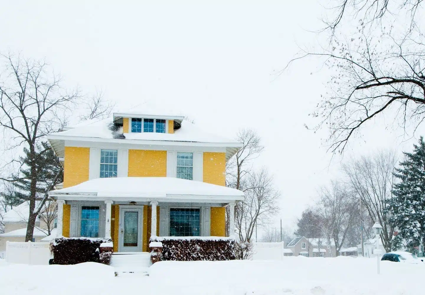 A yellow home covered in snow
