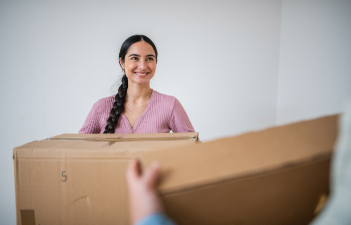 A woman is smiling as she receives used moving boxes for free from someone who doesn’t need them anymore.