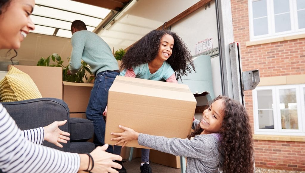 Family unloading moving boxes from rental truck