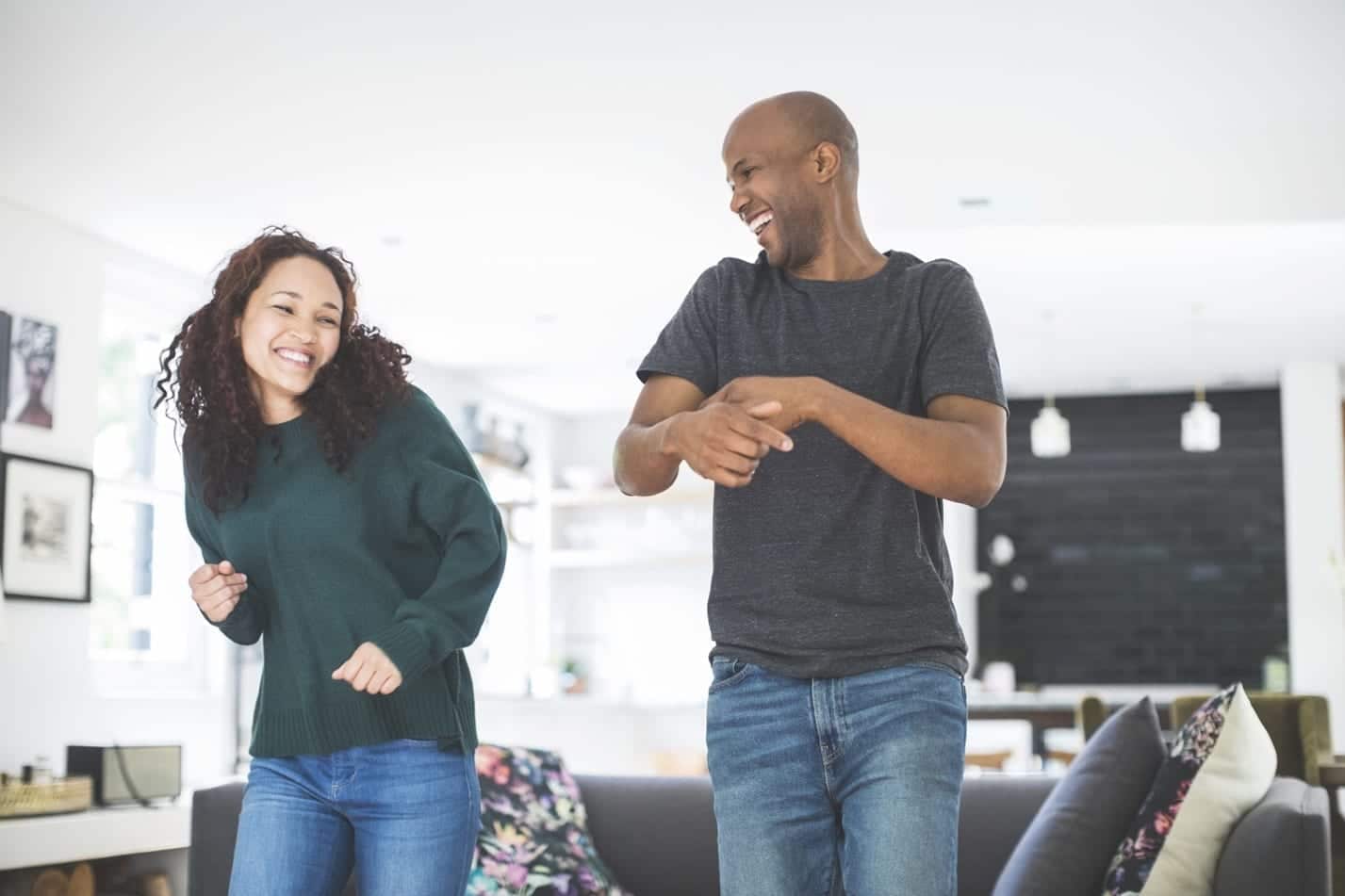 A cute young couple dances, celebrating their move in their new living room. 