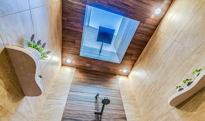 A beautiful shower with the shower head installed in a sunroof, making it seem as if you're showering in the rain