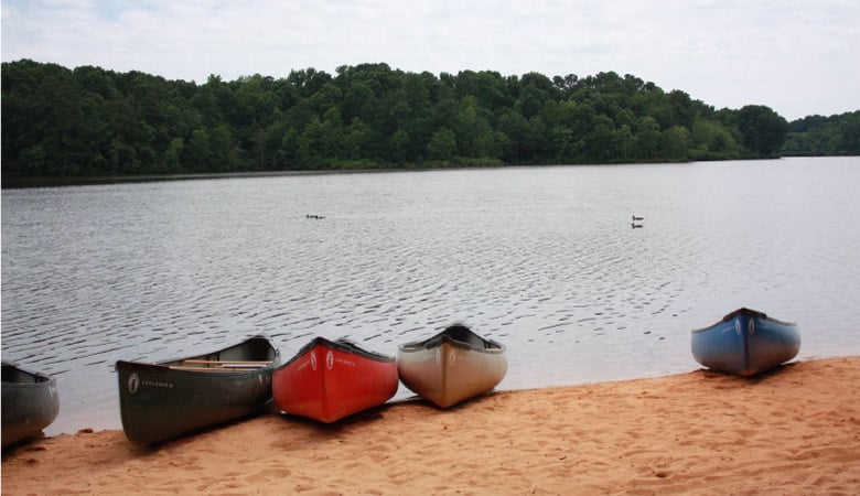 Canoes are resting on the sandy beach of Bass Lake in Holly Springs, North Carolina.