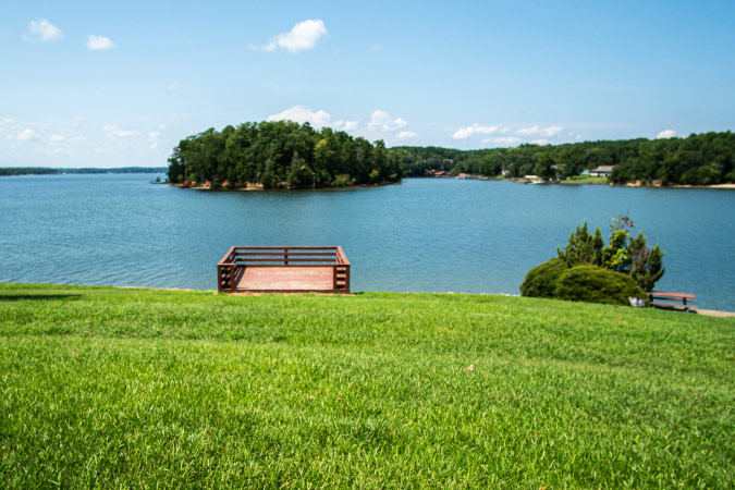 View of the water from Lake Wylie Park in Tega Cay, South Carolina, featuring lush green foliage and a light blue sky.