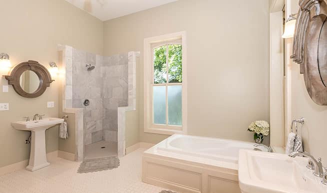 A beige bathroom is augmented by an angular, stone, doorless shower