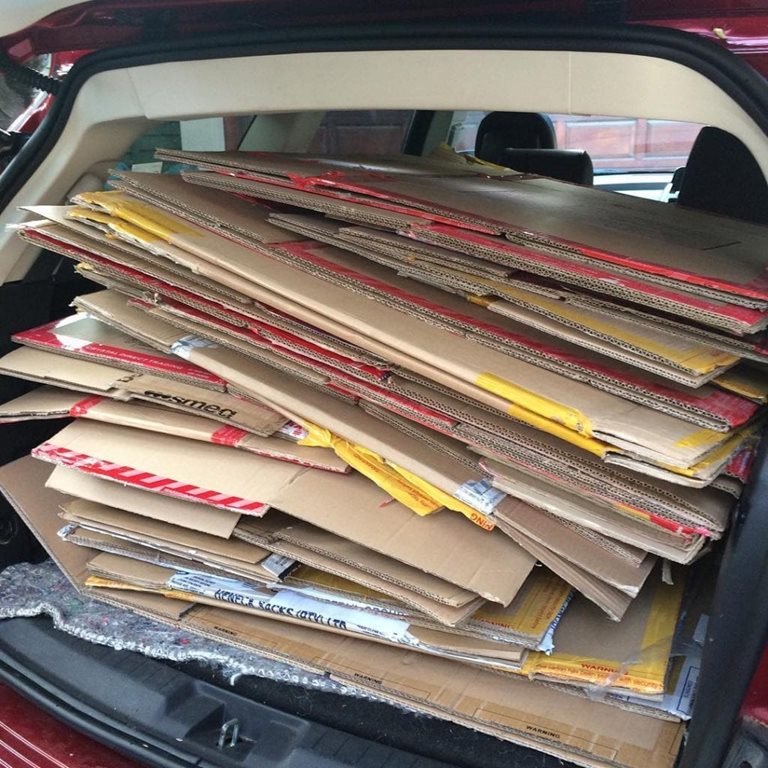 A stack of flattened cardboard boxes loaded in the back of a car