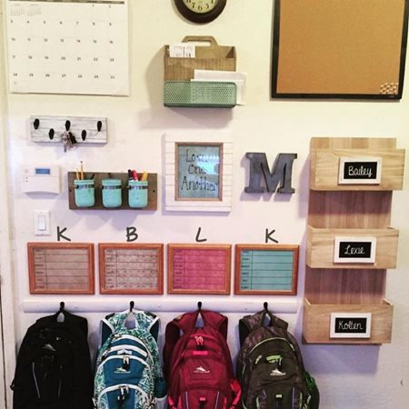 A neatly organized wall for the kids, including backpacks, keys, and school supplies
