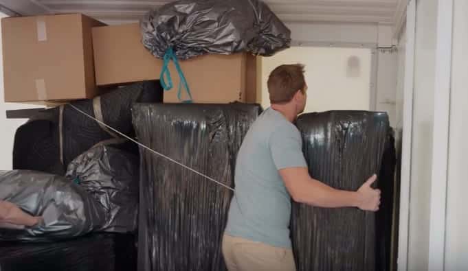 A man loads items wrapped in garbage bags