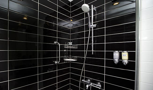 A reversal of a usual subway tile shower: the tiles are black with white accents