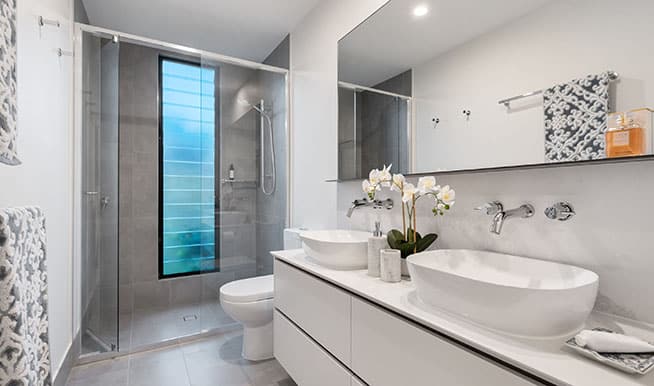 A clean, simple bathroom made whole by a few key details: a shower frame that blends in with the wall, a few orchids, and a large window