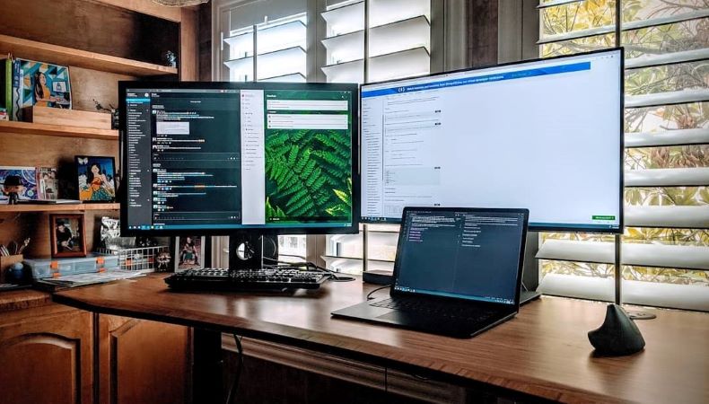 A home office setup that features a laptop and two additional, very large monitors for easy work.