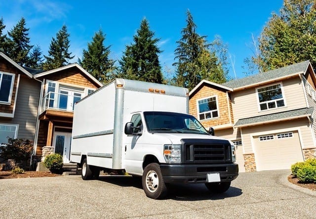 A white moving truck sitting outside a residential home, ready to be loaded