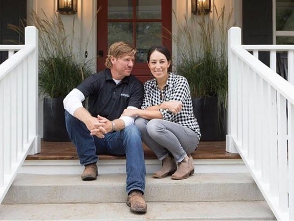 Chip and Joanna Gaines from HGTV's "Fixer Upper" channel sit on the stairway to a home and smile