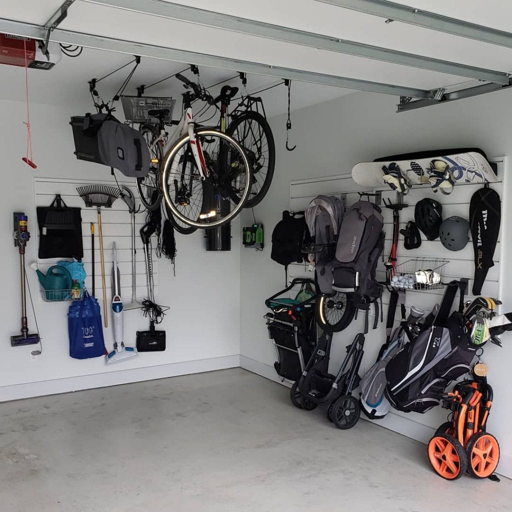 A sleek, vertical storage system being used to store yard tools, sporting equipment, strollers, etc. out of the way in a garage.