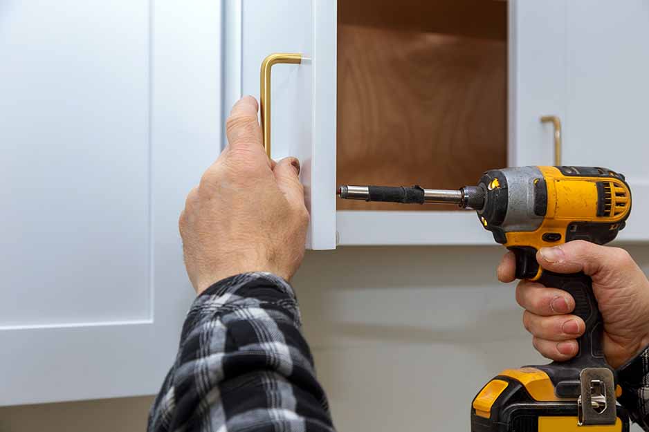 A man replacing his kitchen cabinet door handles