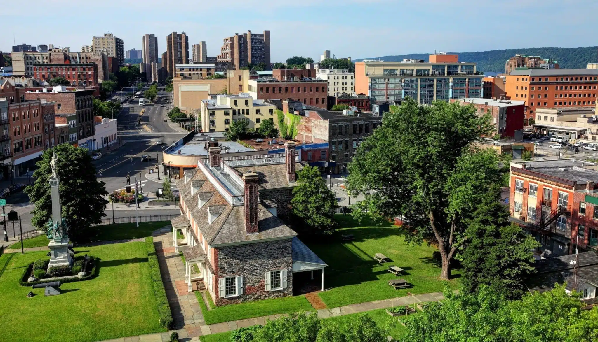 Aerial view of a New York City suburb with several large brick and stone buildings and a couple of lush green spaces.