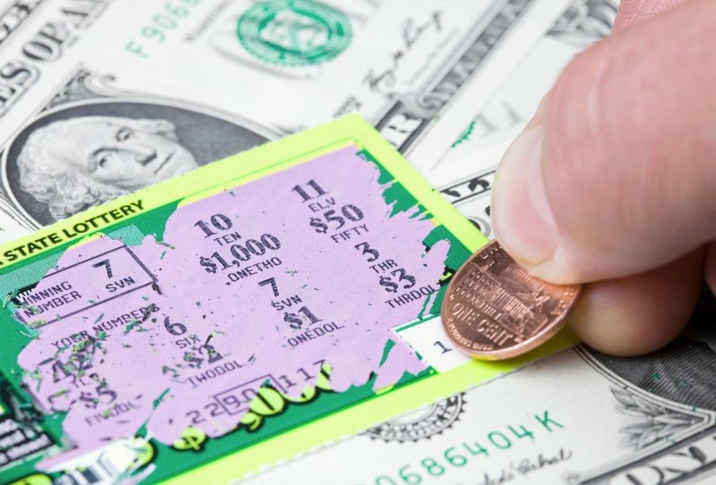 Someone using a penny to play a scratch-off card