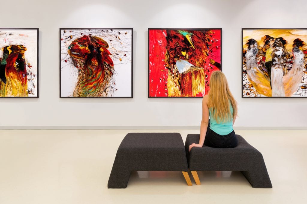 A woman sitting in a museum while looking at colorful art