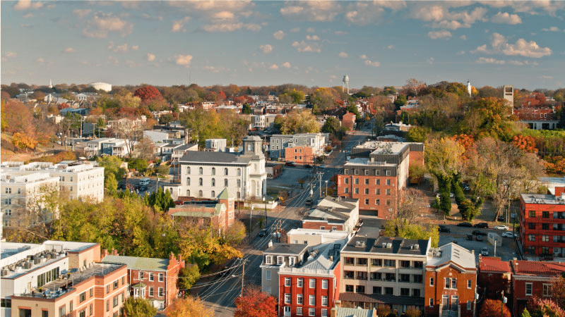 Aerial view of the Shockoe Bottom and Church Hill neighborhoods in Richmond, Virginia. Many buildings are large and have sharp angles and evenly set windows. It’s early autumn and, while some trees are still green, the leaves on others have already begun to change color.