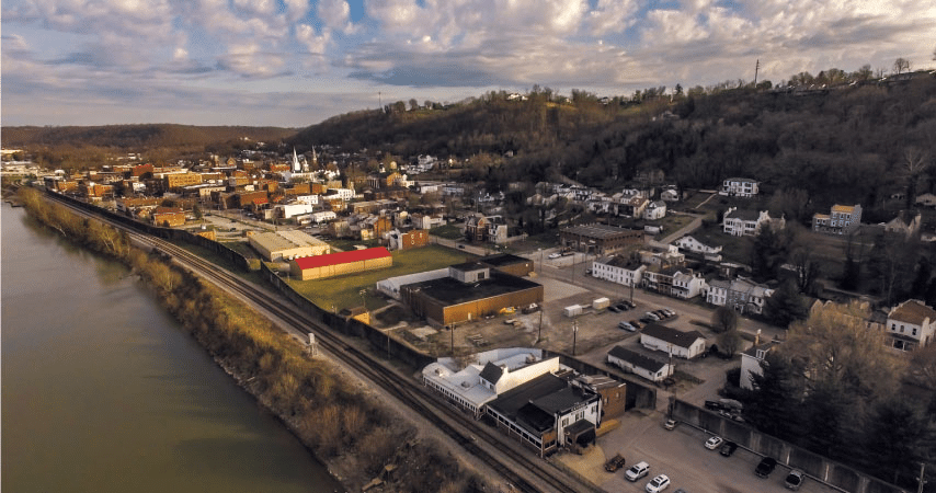 Aerial view of Maysville, Kentucky, along the Ohio River. It’s a partially cloudy day and the occasional beam of sunshine is still reaching down upon the town. 