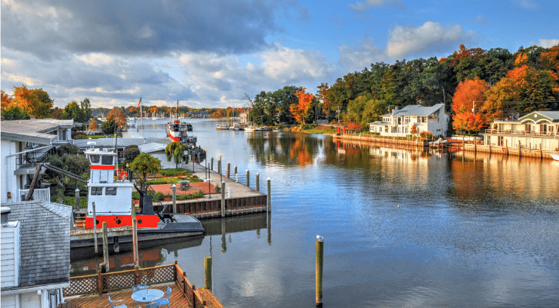 Lovely waterfront homes in Saugatuck, Michigan in the early autumn. Docks line the waterway and boats are peacefully moving out toward Lake Michigan.