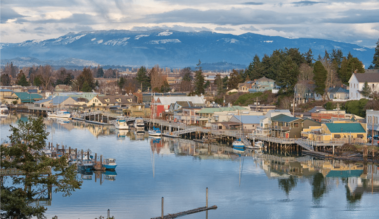 Waterfront homes along the Swinomish Channel in La Conner, a small town in Washington state. It’s an overcast day and there are mountains in the distance. 