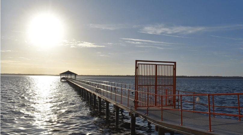The sun sits low in the sky and shines brightly off the water along the pier at Moosehaven retirement community in Orange Park, Florida.